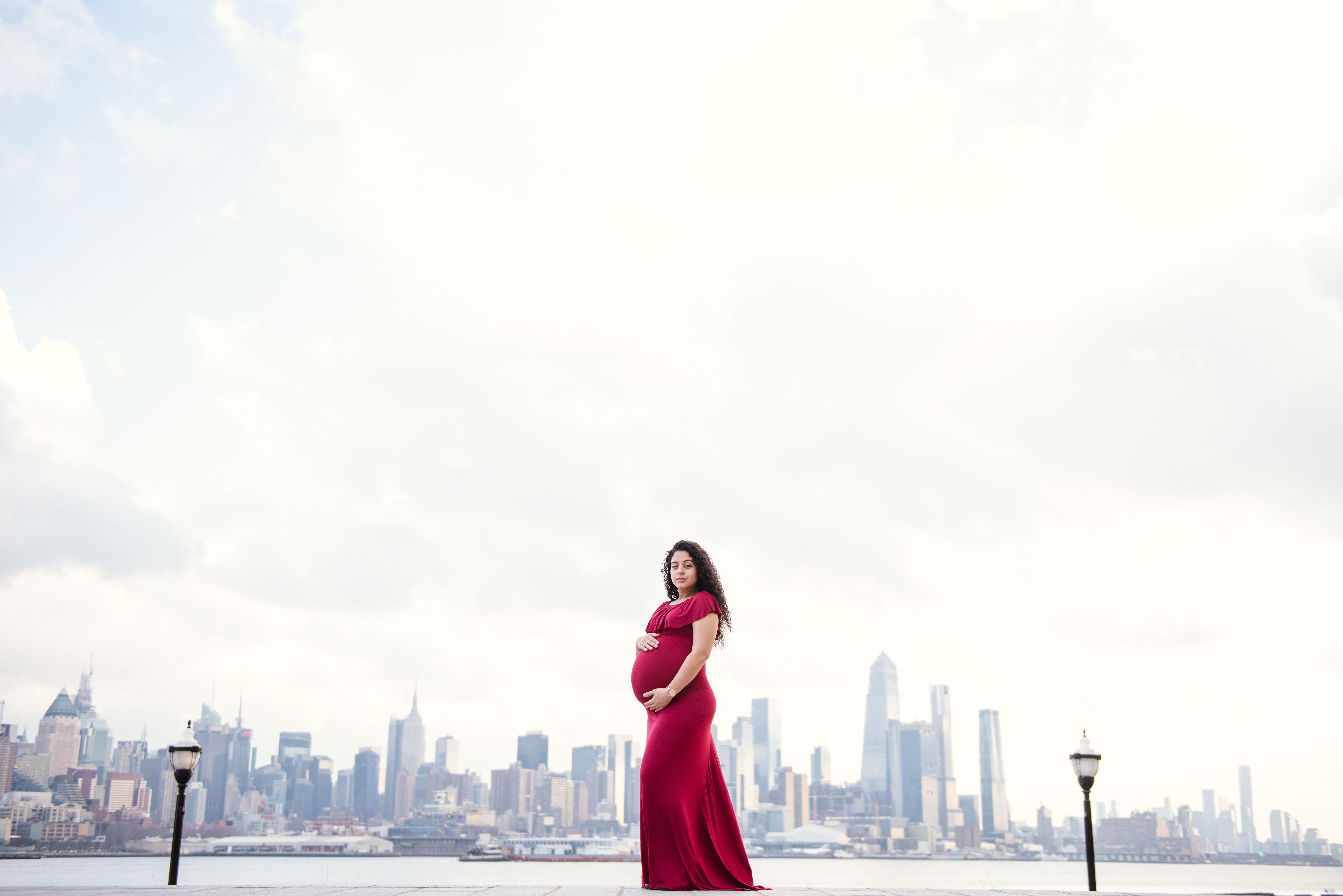 A woman in a pink dress standing in front of a white sheet